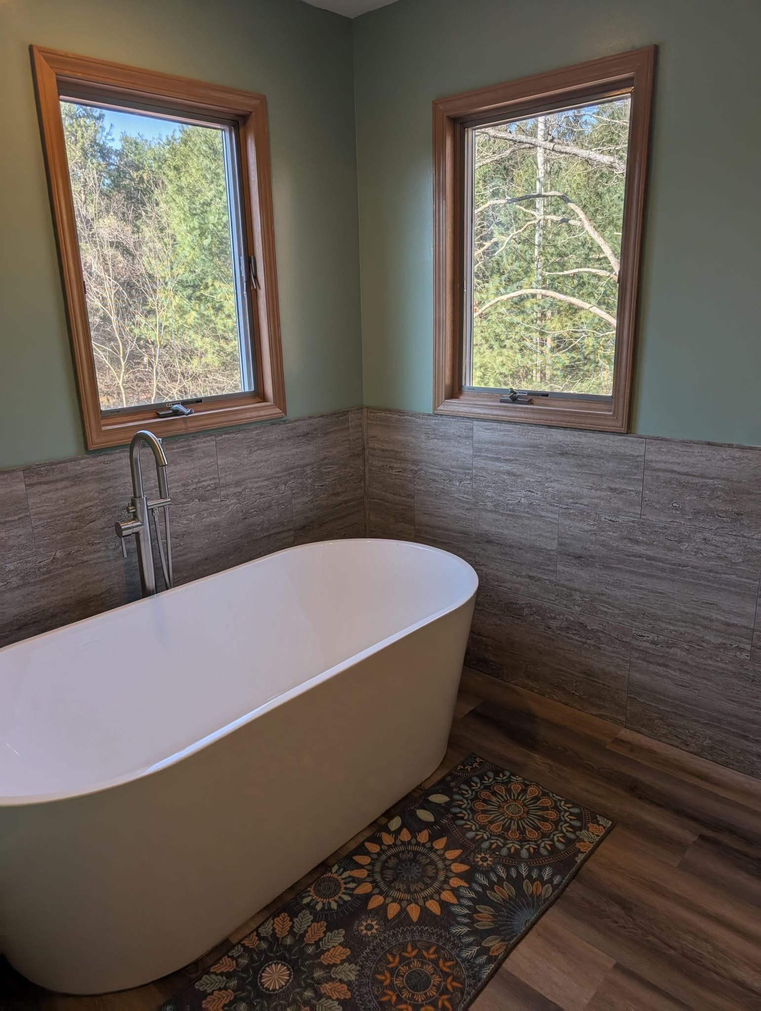 Luxury freestanding tub with wood-look tile wainscoting and natural views